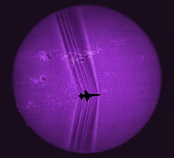 A T-38 trainer photographed against the sun — multiple shock waves visible as light-distorting boundaries from nose, air intakes, wings, and tail